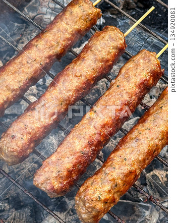 Grilled kebabs on skewers sizzling over open flame barbecue. 134920081