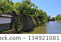 A view of the stone walls leading to the edge of the Wakayama Castle moat under blue skies and fresh greenery 134921081
