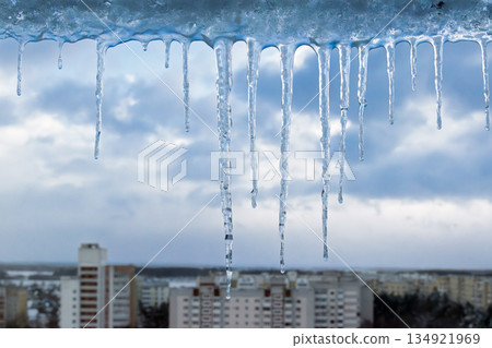 Long winter icicles hanging above city skyline in cold weather Long winter icicles hanging above city skyline in cold weather 134921969