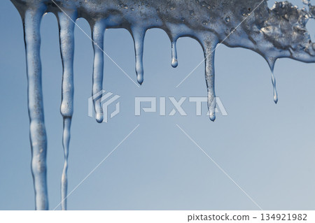 Winter icicles hanging against blue sky closeup Winter icicles hanging against blue sky closeup 134921982
