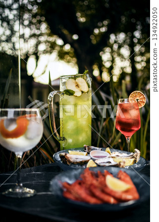 Mixed cocktail drinks and sangria with snacks on restaurant table outdoors at sunset 134922050