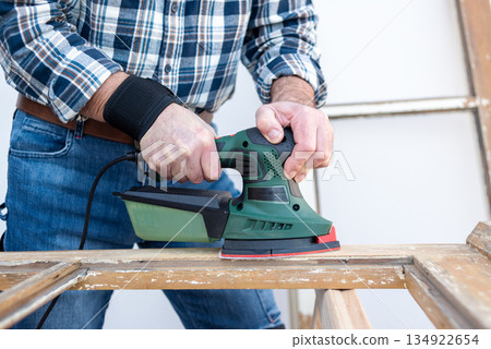 Carpenter at work, restoring an old wooden window. Carpentry. 134922654