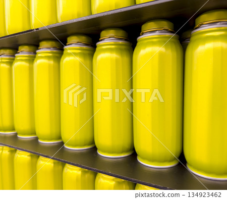 Bright yellow jars, metallic tins, soda bottles arranged on shelves. The repeating pattern of Bright yellow jars, metallic tins, soda bottles arranged on shelves. The repeating pattern of 134923462