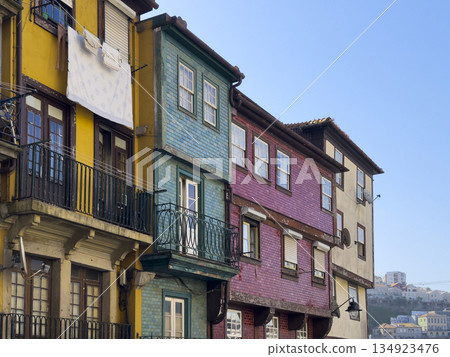 Colorful traditional houses in Porto with tiled facades in yellow, green, and red. Laundry hangs 134923476