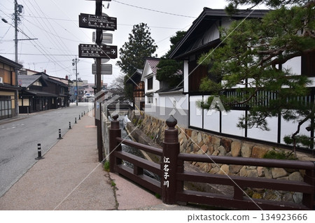 日本岐阜縣高山市的古老街景。古老的房屋散發著歷史氣息。指示旅遊景點的路標,以及一條穿過城市的溪流。 日本岐阜縣高山市的古老街景。古老的房屋散發著歷史氣息。指示旅遊景點的路標,以及一條穿過城市的溪流。 134923666