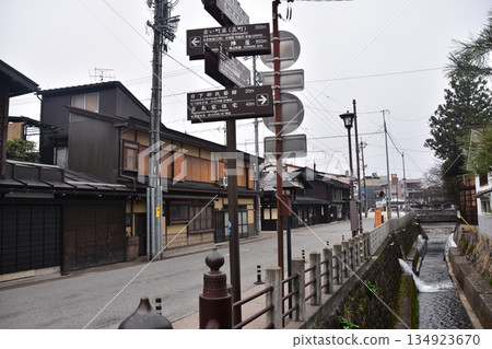 日本岐阜縣高山市的古老街景。古老的房屋散發著歷史氣息。指示旅遊景點的路標,以及一條穿過城市的溪流。 日本岐阜縣高山市的古老街景。古老的房屋散發著歷史氣息。指示旅遊景點的路標,以及一條穿過城市的溪流。 134923670