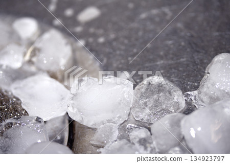 Melting ice cubes dripping down a sink plug drain silver metal basin 134923797