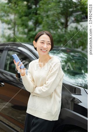 一位女士手持智慧型手機，開著汽車，她的私家車。 134924028