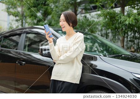 一位女士手持智慧型手機,開著汽車,她的私家車。 一位女士手持智慧型手機,開著汽車,她的私家車。 134924030