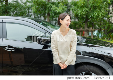 一位中年婦女站在一輛車前 134924081