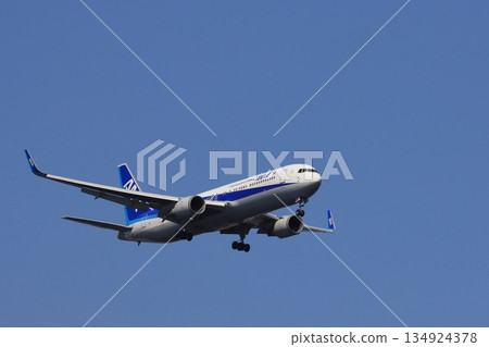 一架客機在藍天背景下降落。一架正在進場的全日空飛機。 134924378