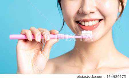 微笑的女子手持牙刷，背景為藍色。 134924875