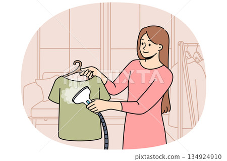 Woman housewife uses steam iron to treat clothes after washing and avoid wrinkles 134924910