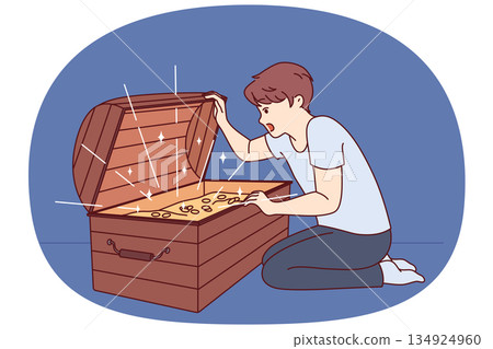 Little boy has found treasure with gold coins and joyfully opens mouth seeing contents of chest 134924960