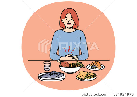 Girl suffers from stomach pain due to digestive problems, sits at dinner table with food 134924976