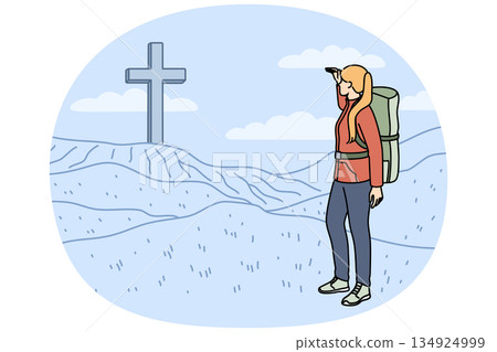 Woman pilgrim stands near large christian cross on hills during hike to sites of ancient cities Woman pilgrim stands near large christian cross on hills during hike to sites of ancient cities 134924999