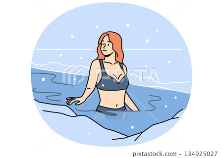 Woman bathes in ice hole on orthodox holiday of baptism, standing in icy water under falling snow Woman bathes in ice hole on orthodox holiday of baptism, standing in icy water under falling snow 134925027