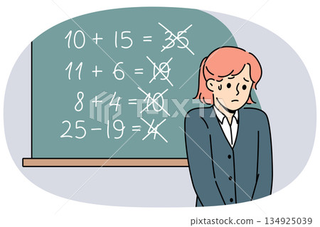 Upset schoolgirl stands near blackboard, sad because of mistakes in solving mathematical examples 134925039
