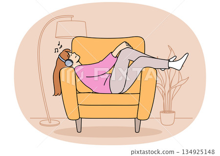 Relaxed woman wearing headphones lies on sofa listening to music and relaxing after hard day at work Relaxed woman wearing headphones lies on sofa listening to music and relaxing after hard day at work 134925148