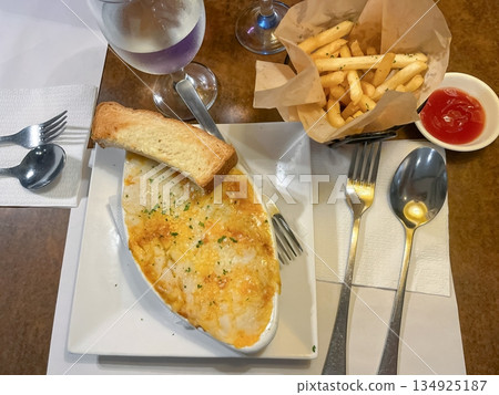 Lasagna and French fries served on plates on a table in a restaurant Lasagna and French fries served on plates on a table in a restaurant 134925187