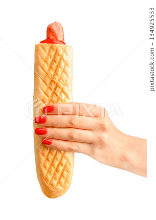 Hot dog in female hand with red manicure isolated on white background Hot dog in female hand with red manicure isolated on white background 134925533