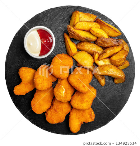 Chicken nuggets with potato wedges and sauces on black slate plate isolated on white background Chicken nuggets with potato wedges and sauces on black slate plate isolated on white background 134925534