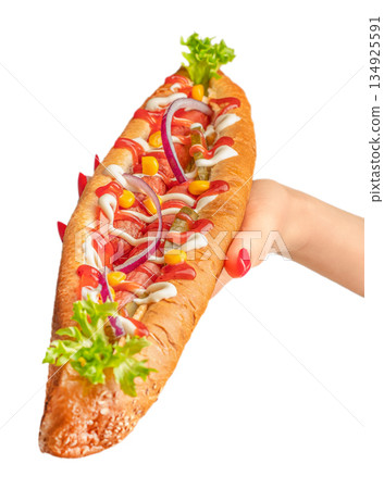 Hot dog sandwich with sausage, vegetables and sauces held in female hand isolated on white background 134925591