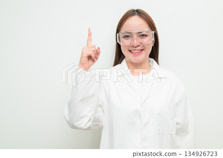 Portrait of Asian female research scientist against white background pointing finger Portrait of Asian female research scientist against white background pointing finger 134926723