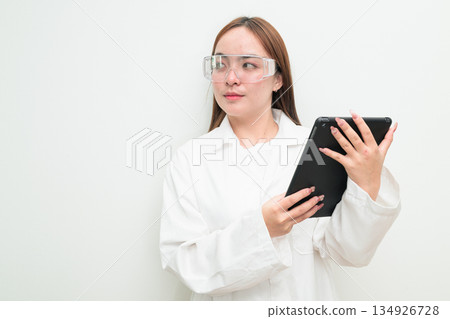 Portrait of Asian female research scientist against white background using digital tablet computer Portrait of Asian female research scientist against white background using digital tablet computer 134926728
