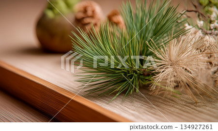 木質表面上裝飾著松針和乾樹枝。 木質表面上裝飾著松針和乾樹枝。 134927261