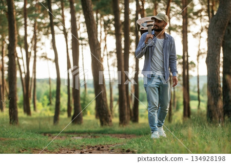 Walking forward. Handsome man is in the forest with acoustic guitar 134928198