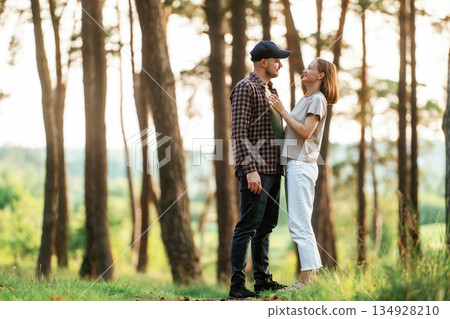Looking at each other. Lovely couple are together in the forest at summer daytime Looking at each other. Lovely couple are together in the forest at summer daytime 134928210