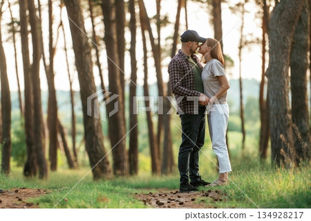 Looking at each other. Lovely couple are together in the forest at summer daytime Looking at each other. Lovely couple are together in the forest at summer daytime 134928217
