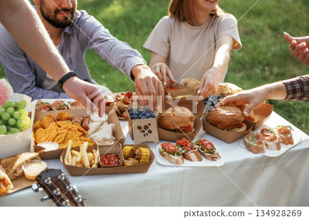Enjoying the meal. Group of friends are having picnic on the field with food in eco boxes 134928269