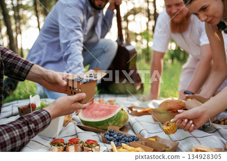 Conception of free time, wellness. Group of friends are having picnic on the field with food in eco boxes 134928305