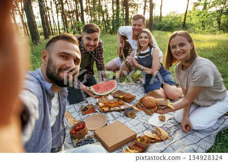 Making the selfie, sitting. Group of friends are having picnic on the field with food in eco boxes 134928324
