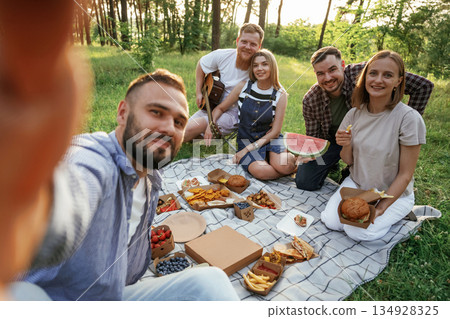 Making the selfie, sitting. Group of friends are having picnic on the field with food in eco boxes 134928325