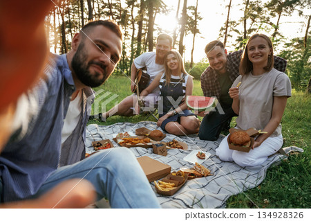 Making the selfie, sitting. Group of friends are having picnic on the field with food in eco boxes 134928326