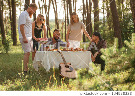 Positive mood, having fun. Group of friends are having picnic on the field with food in eco boxes Positive mood, having fun. Group of friends are having picnic on the field with food in eco boxes 134928328