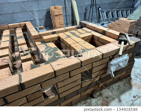 Fresh brickwork of a heating stove ash pit and bench. Smoke channels of the bench are visible. Wide shot. Fresh brickwork of a heating stove ash pit and bench. Smoke channels of the bench are visible. Wide shot. 134928586