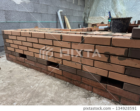 Fresh brickwork of a heating stove bench. Heat outlets of the bench are visible. Fresh brickwork of a heating stove bench. Heat outlets of the bench are visible. 134928591