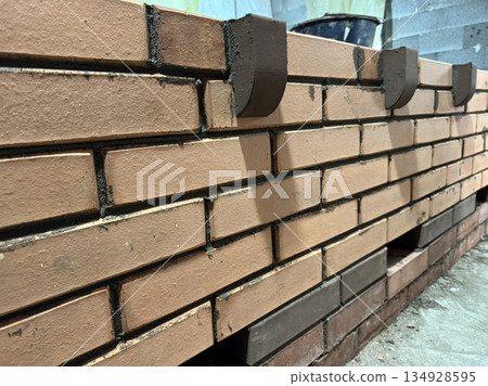 Fresh brickwork of a heating stove bench with decorative elements. Close-up. Fresh brickwork of a heating stove bench with decorative elements. Close-up. 134928595