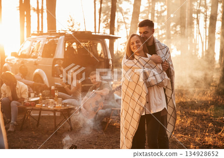 Lovely couple embracing each other, in smoke. Group of friends are together in the forest Lovely couple embracing each other, in smoke. Group of friends are together in the forest 134928652