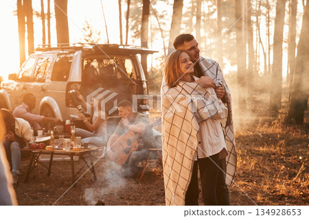 Lovely couple embracing each other, in smoke. Group of friends are together in the forest Lovely couple embracing each other, in smoke. Group of friends are together in the forest 134928653