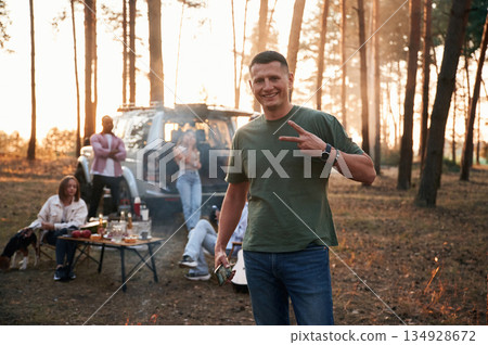 Happy man is smiling. Group of friends are together in the forest Happy man is smiling. Group of friends are together in the forest 134928672