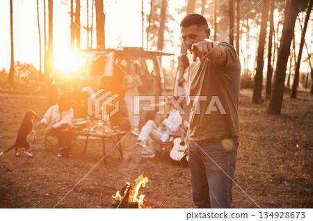 Happy man is smiling. Group of friends are together in the forest Happy man is smiling. Group of friends are together in the forest 134928673