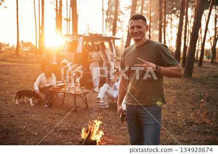 Happy man is smiling. Group of friends are together in the forest Happy man is smiling. Group of friends are together in the forest 134928674