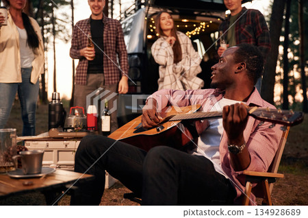 Acoustic guitar player. Group of friends are together in the forest 134928689
