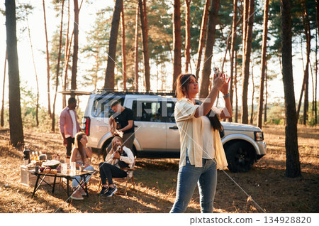 Woman is taking photo of nature. Group of friends are together in the forest Woman is taking photo of nature. Group of friends are together in the forest 134928820