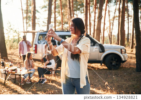 Woman is taking photo of nature. Group of friends are together in the forest Woman is taking photo of nature. Group of friends are together in the forest 134928821